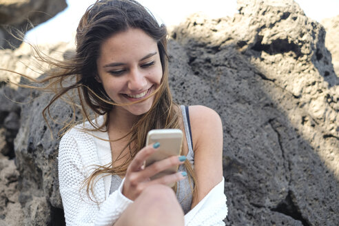 Porträt eines lächelnden Teenagers, der auf sein Smartphone schaut - SIPF000298