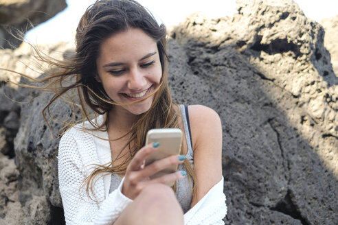 Portrait of smiling teenage girl looking at smartphone - SIPF000298