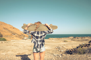 Spain, back view of teenage girl with longboard on shoulders - SIPF000304