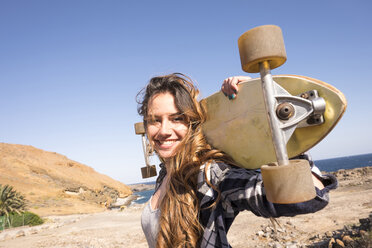 Spain, portrait of smiling teenage girl with longboard on shoulders - SIPF000305