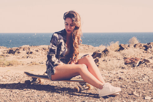 Spanien, jugendliches Mädchen auf Longboard sitzend - SIPF000308