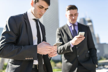 USA, Los Angeles, two businessmen looking at cell phones - LEF000006