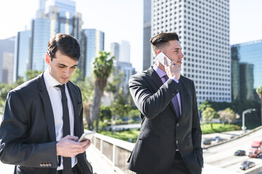 USA, Los Angeles, two businessmen using cell phones - LEF000009