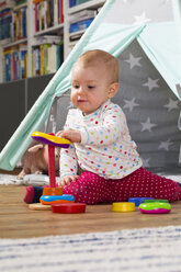 Baby girl playing with wooden toys on the floor at home - WWF003937