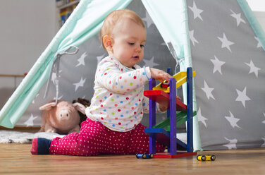 Baby Mädchen spielt mit Holzspielzeug auf dem Boden zu Hause - WWF003938