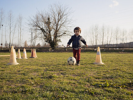 Kleiner Junge spielt Fußball auf Gras zwischen Verkehrskegeln - XCF000070