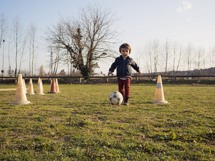 Little boy playing soccer on grass among traffic cones - XCF000070