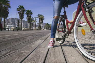 Leg of young woman sitting on bicycle - ABZF000309