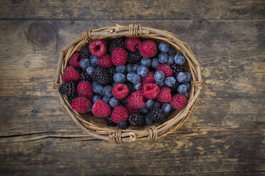 Wickerbasket of different wild berries on wood - LVF004680