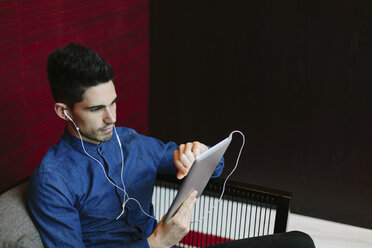 Young businessman with earphones using digital tablet - BOYF000242