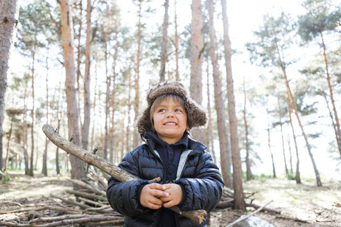 Porträt eines kleinen Jungen, der mit einem Ast im Wald spielt - VABF000389