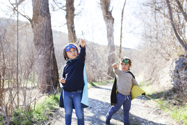 Two little boys dressed up as a superheros posing on a path - VABF000391