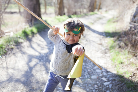 Kleiner Junge, verkleidet als Superheld, posiert auf einem Weg, lizenzfreies Stockfoto