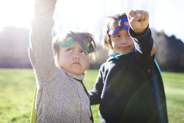 Zwei kleine Jungen als Superhelden verkleidet posieren auf einer Wiese - VABF000393