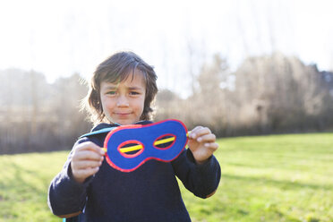 Portrait of little boy showing his superhero eye mask - VABF000396