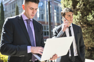 Two businessmen outdoors with laptop and cell phone - LEF000022