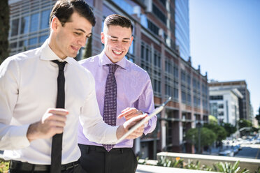 Two smiling businessmen outdoors looking at tablet - LEF000035