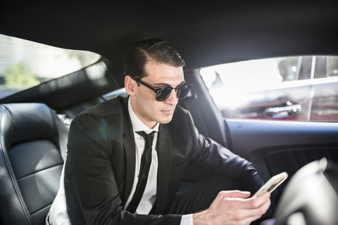 Geschäftsmann im Auto mit Mobiltelefon, lizenzfreies Stockfoto