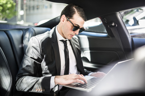 Geschäftsmann im Auto mit Laptop, lizenzfreies Stockfoto