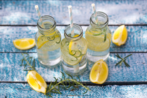 Zitronenscheiben und Rosmarin in Wasserflaschen, Trinkhalme, lizenzfreies Stockfoto