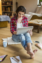 Junge Frau zu Hause bei der Arbeit mit einem digitalen Tablet - HAPF000266