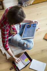 Junge Frau arbeitet zu Hause mit digitalem Tablet und macht sich Notizen - HAPF000276