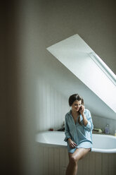 Young woman in bathroom using smartphone - HAPF000287