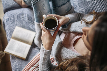 Junge Frau zu Hause mit einer Tasse Kaffee und einem Buch - HAPF000301