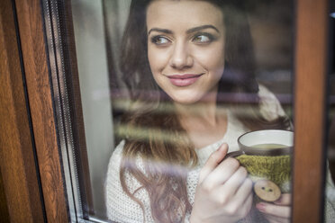 Junge Frau am Fenster stehend mit einer Tasse Kaffee - HAPF000321