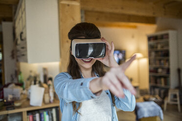 Young woman at home using Virtual Reality goggles - HAPF000333