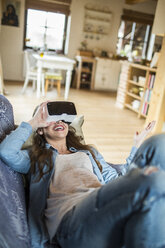 Young woman at home using Virtual Reality goggles - HAPF000336