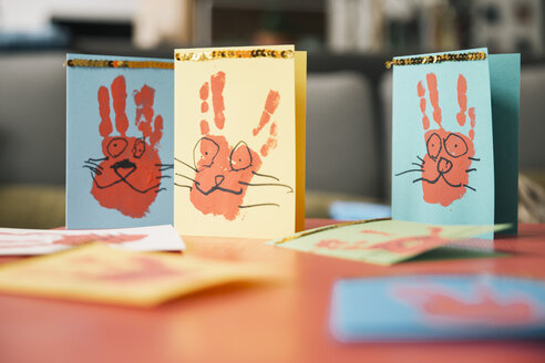 Selbstgemachte Osterhasenkarten mit Handabdrücken auf einem Tisch - MFF002958