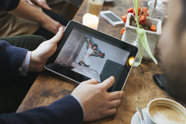 Mann in einem Café zeigt Freunden ein Bild auf einem digitalen Tablet - JUBF000125