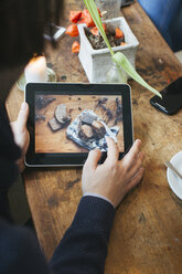 Mann in einem Café zeigt Bild auf digitalem Tablet - JUBF000126