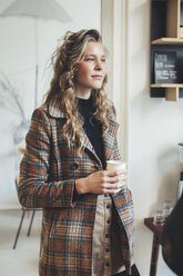 Junge Frau hält Tasse in einem Cafe - JUBF000141