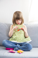 Porträt eines stickenden kleinen Mädchens, das auf einer Couch sitzt - LVF004703