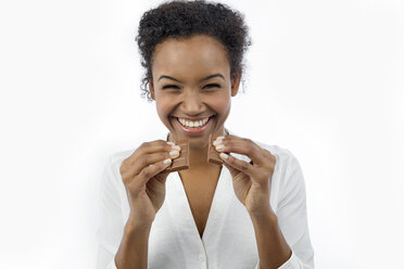 Porträt einer glücklichen jungen Frau mit einem Schokoriegel vor einem weißen Hintergrund - GDF000973