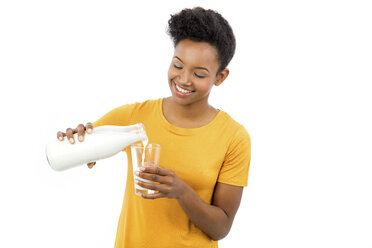 Porträt einer lächelnden jungen Frau, die Milch in ein Glas gießt, vor einem weißen Hintergrund - GDF000980