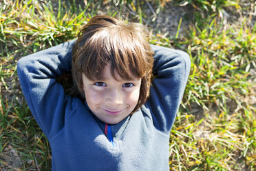 Portrait of smiling boy sitting in meadow - VABF000414