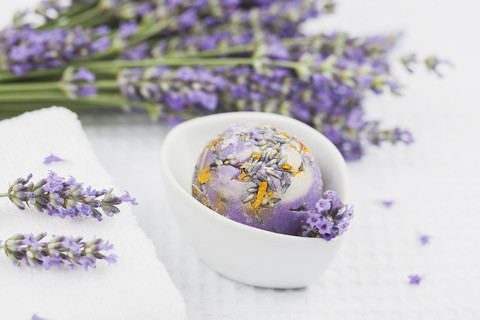 Wellnessartikel, Lavendel-Calendula-Seife Kugel in Schale, Lavendel, weißes Handtuch, lizenzfreies Stockfoto