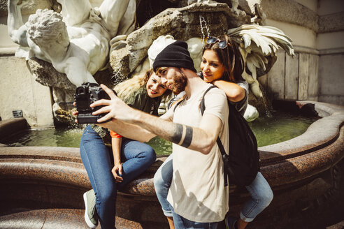 Austria, Vienna, group of three friends taking a selfie in front of fountain at Hofburg Palace - AIF000289