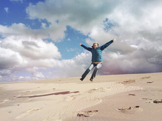 Belgium, Flanders, North Sea Beach, woman jumping down sand dune - GWF004660