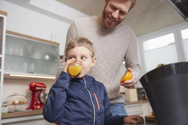Vater mit Sohn trinkt in der Küche frisch gepressten Orangensaft - RHF001378