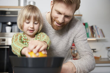 Vater und Tochter benutzen eine Saftpresse in der Küche - RHF001384