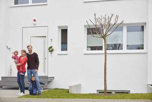 Porträt einer glücklichen Familie mit schwangerer Mutter vor einem Haus - RHF001399