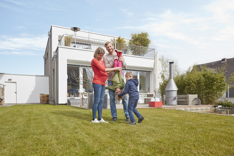 Porträt einer glücklichen Familie mit schwangerer Mutter im Garten, lizenzfreies Stockfoto