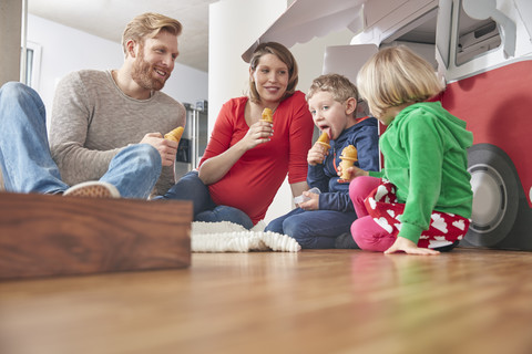 Glückliche Familie mit Eis am Stiel und Modellauto im Wohnzimmer, lizenzfreies Stockfoto