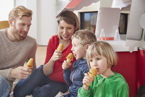 Glückliche Familie mit Eis am Stiel und Modellauto im Wohnzimmer, lizenzfreies Stockfoto