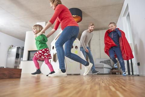 Glückliche Familie beim Laufen im Wohnzimmer, lizenzfreies Stockfoto