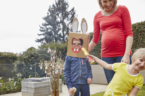 Schwangere Mutter mit Junge mit Hasenmaske und fröhlichem Mädchen im Garten - RHF001423